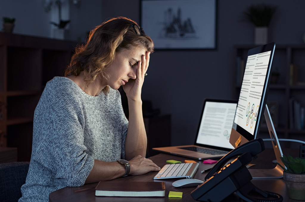 Mujer agotada frente a la computadora, representando el agotamiento docente
